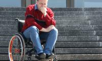 Mand sidder i kørestol på en trappe
