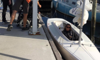 Handicapsejllads. Vibeke sidder i sejlbåd. Til venstre, på molen, holder hendes kørestol og nogle hjælpere. 