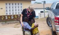 To ghanesiske børn med udviklingshandicap giver en kvinde fra Spejderhjælpens bestyrelse et stort kram