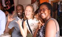 Tre mennesker der smiler under et besøg i Rwanda.